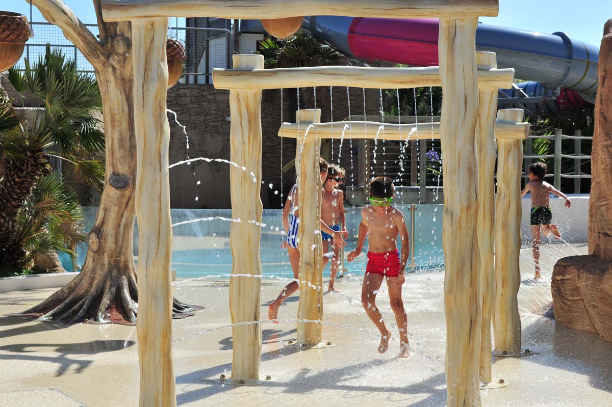 Photo professionnelle d'enfants jouants avec des jets d'eau au camping par Koro Marketing